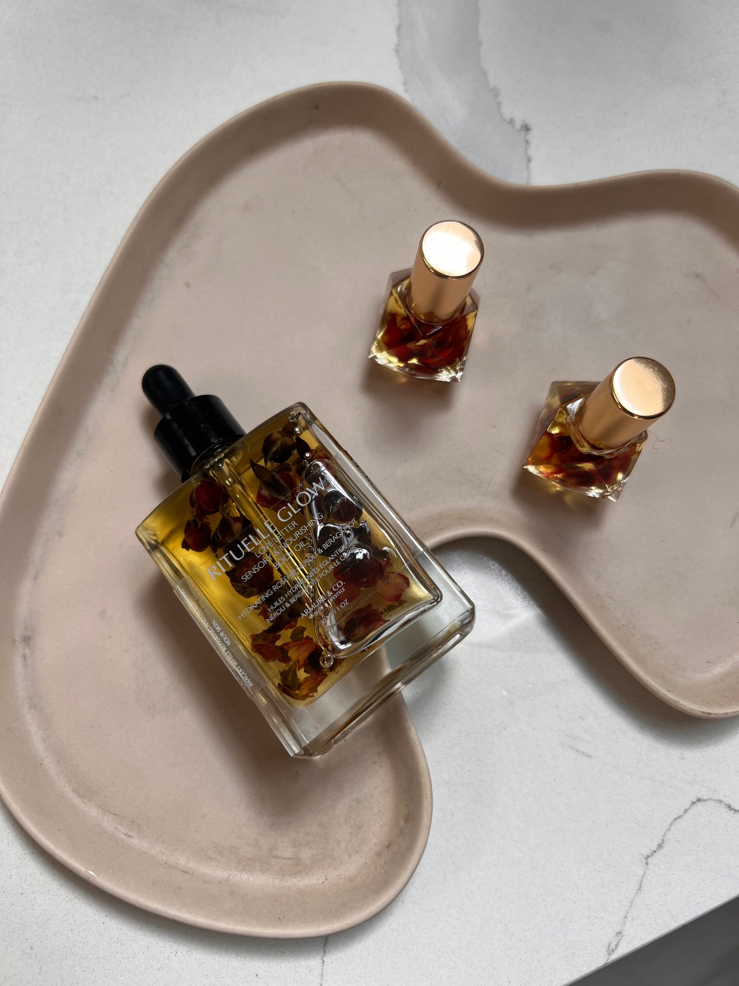 Two perfume oil bottles on a heart-shaped ceramic plate with a light background